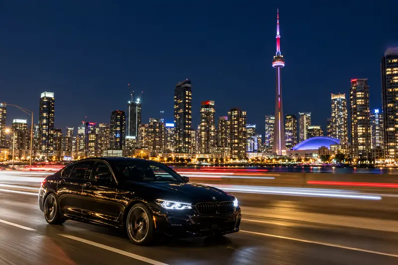 Black sedan on the Gardiner Expressway with the Toronto skyline and CN Tower at night