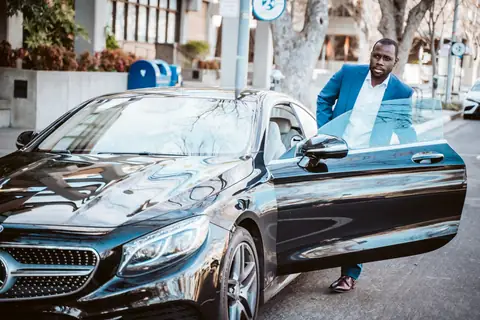 Passenger stepping out of a black Mercedes sedan